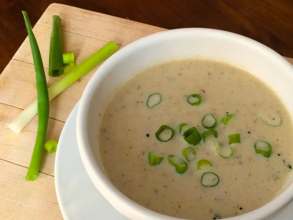 Creamy mushroom soup garnished with chopped green onions.