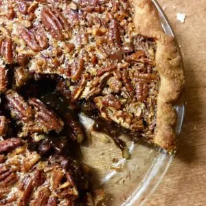 A pecan pie with a slice removed, showing its nutty filling.