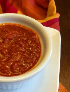 A bowl of rich, red tomato-based sauce on a white plate.
