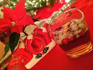 Festive holiday drink with cranberries and a poinsettia plant.