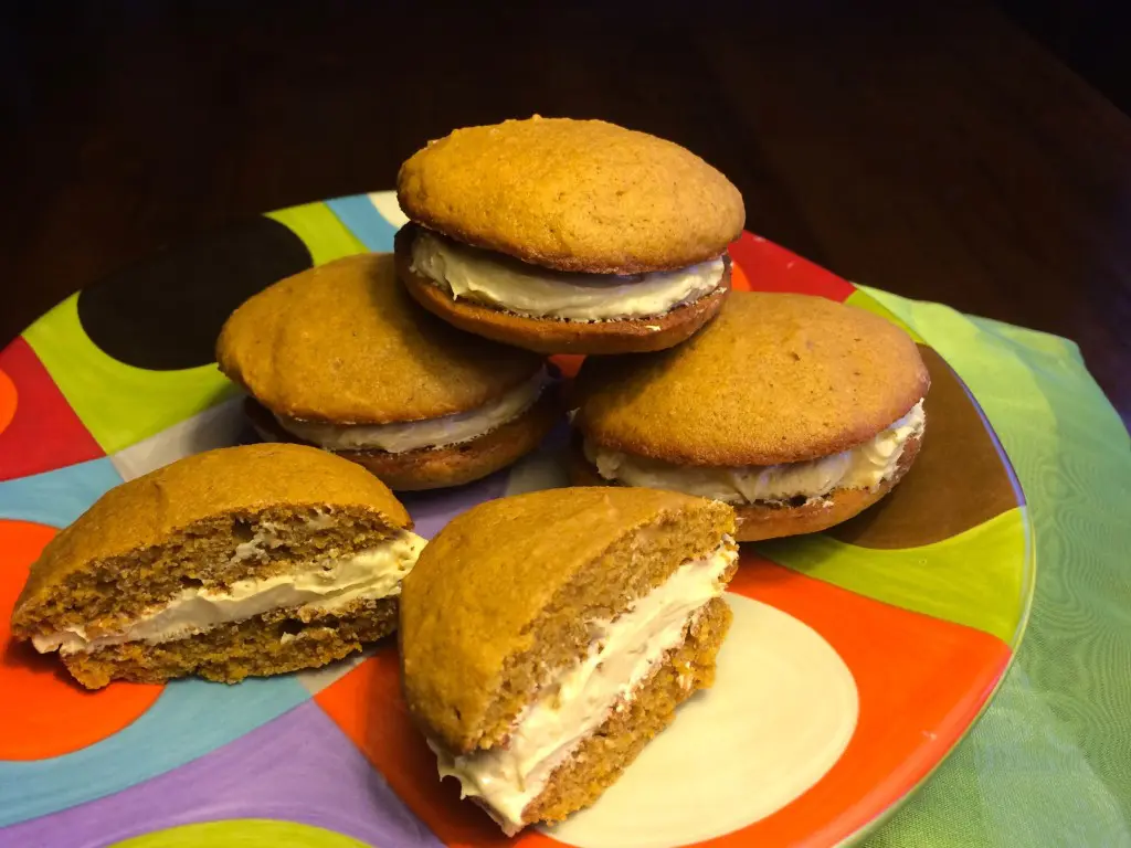 Stack of homemade whoopie pies with creamy filling on a colorful plate.