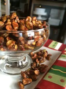 A glass bowl filled with caramel-coated popcorn on a festive tablecloth.