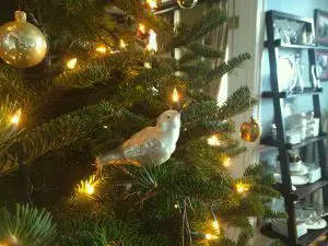 A white bird ornament on a Christmas tree with glowing lights.