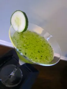 Green kiwi cocktail with a cucumber slice garnish.