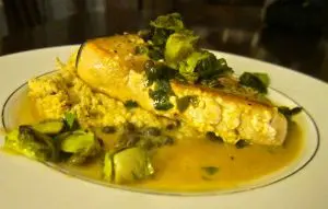 Close-up of a savory fish dish with sauce and garnished greens.