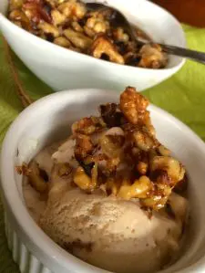 Ice cream topped with caramelized nuts in a white bowl.