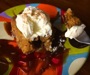 Fried dessert topped with whipped cream and syrup on a colorful plate.
