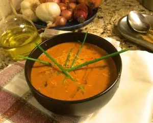A bowl of creamy tomato soup garnished with chives.