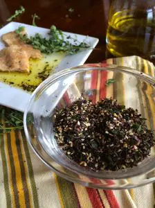A glass bowl filled with dried tea leaves on a striped cloth.