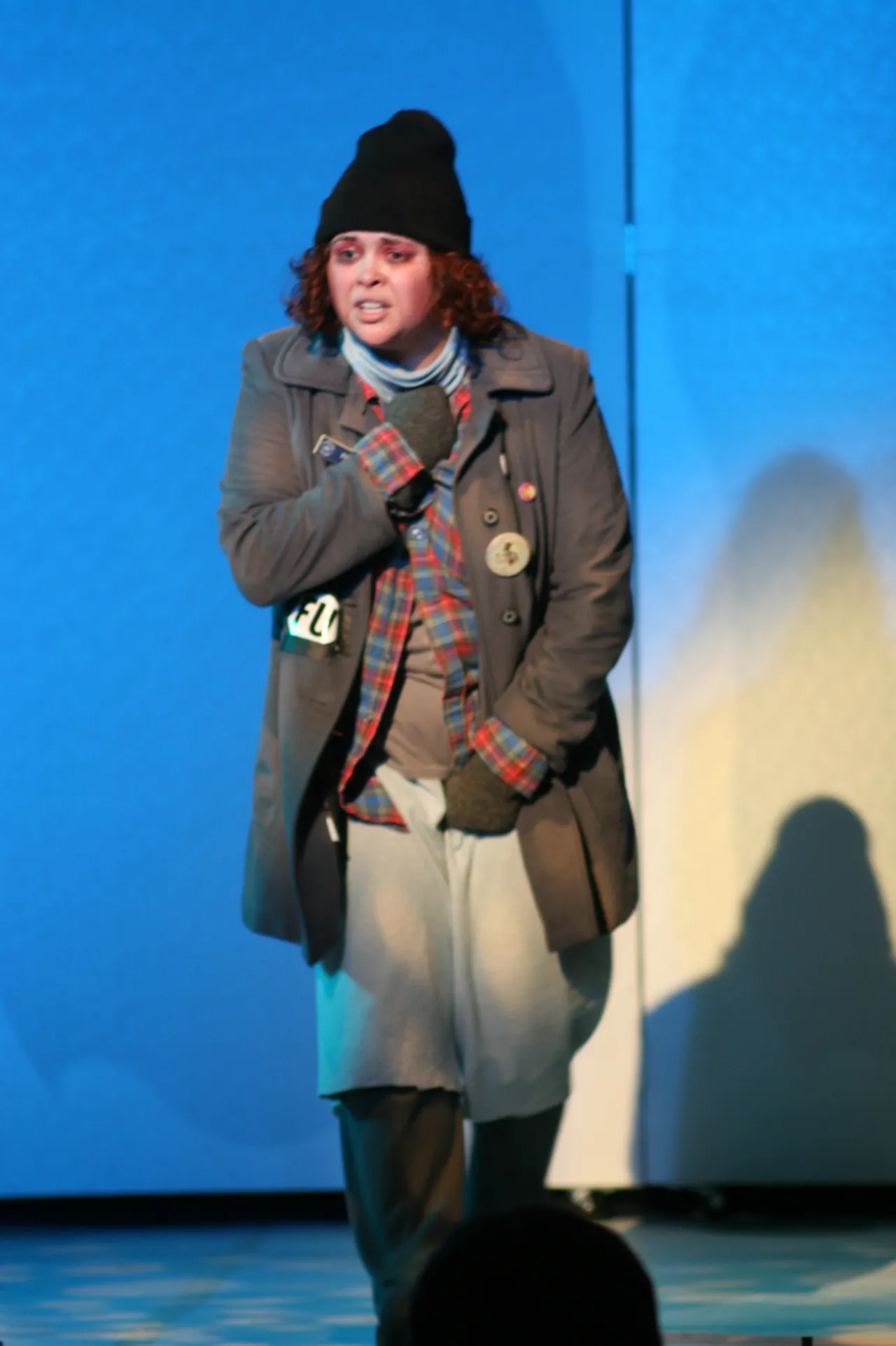 Person dressed in layered winter clothing against a blue background.