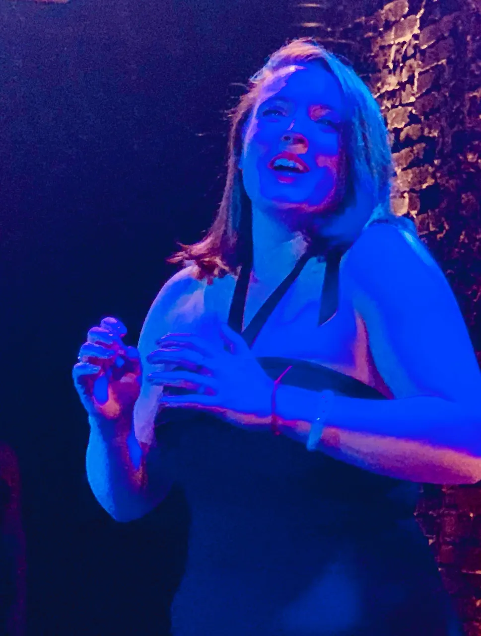 Woman dancing under blue lighting at a nighttime event.