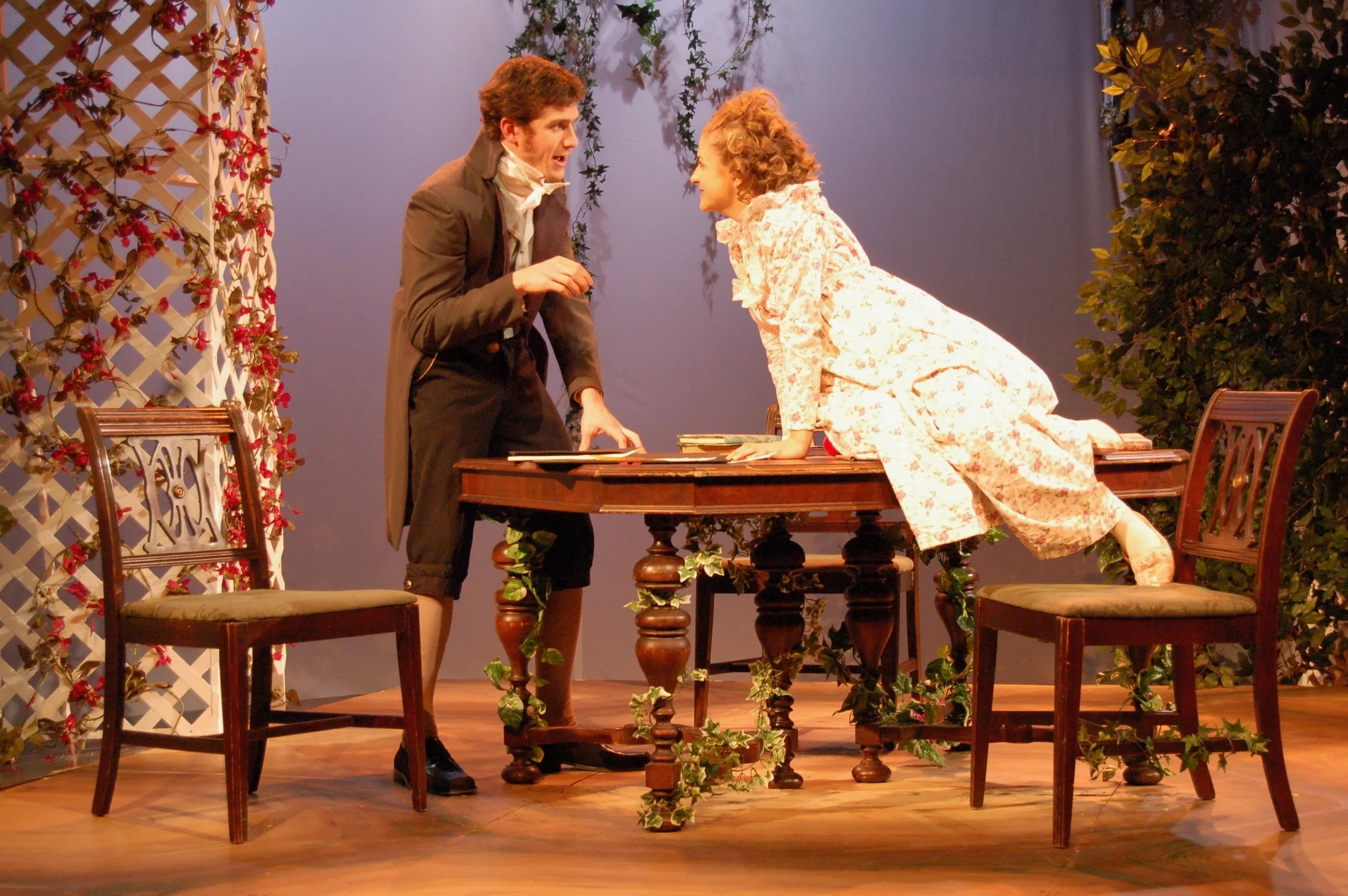 Two actors perform a dramatic scene on a vintage stage set.
