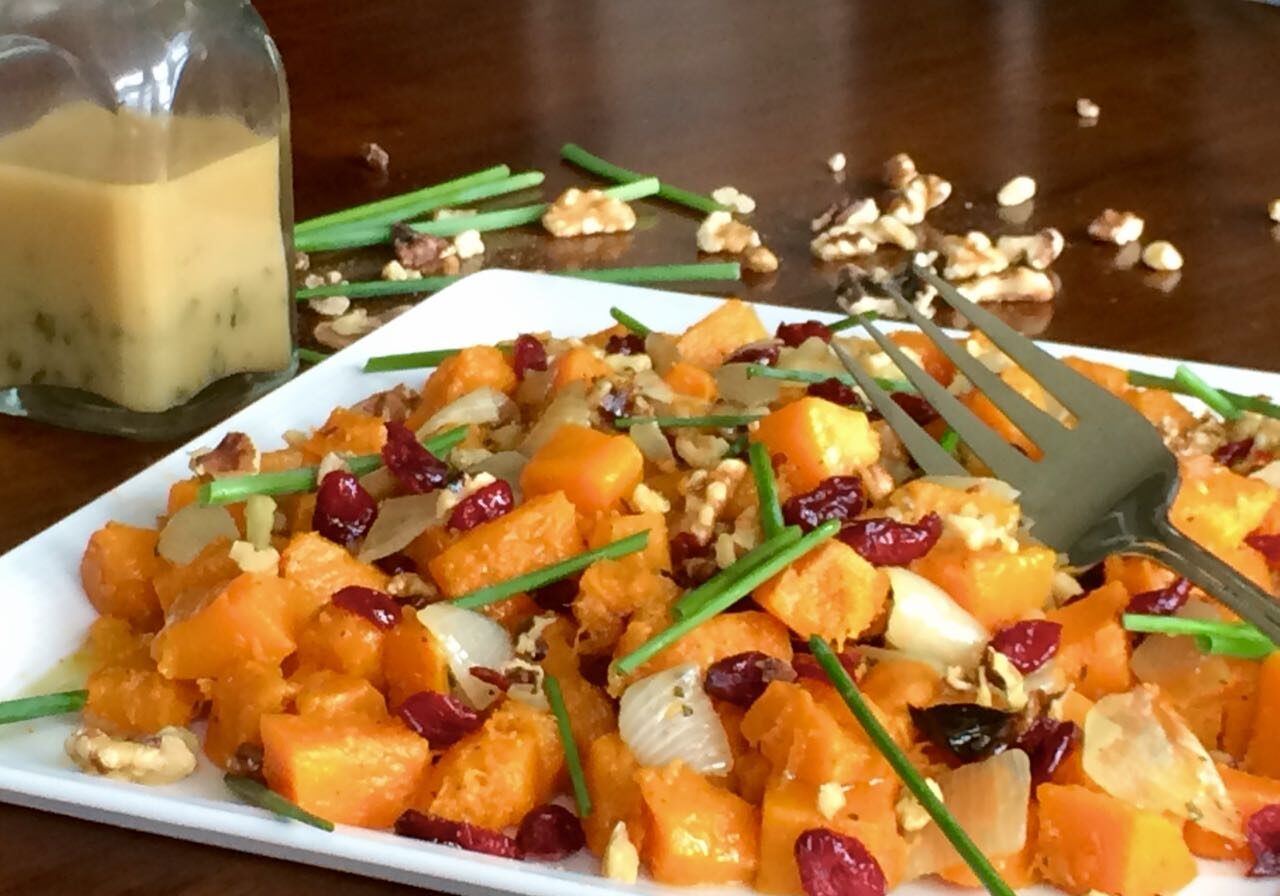 A forkful of roasted butternut squash with cranberries and herbs.
