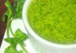 A bowl of vibrant green coriander chutney garnished with fresh cilantro.