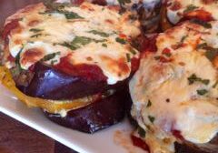 Cheesy baked stuffed eggplants with herbs on a white plate.