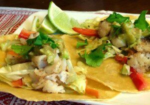 Fresh fish tacos garnished with lime and cilantro on corn tortillas.