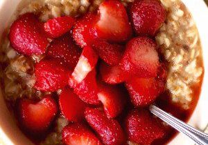 Bowl of oatmeal topped with fresh strawberries and raspberries.
