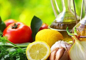 Fresh vegetables and olive oil on a wooden surface.