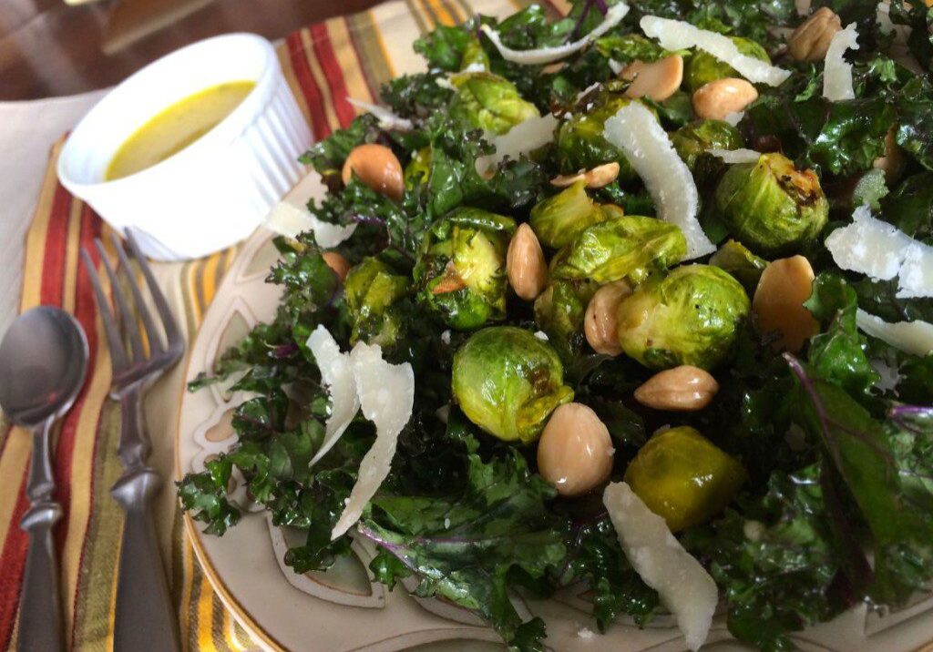 A fresh kale salad with chickpeas, onions, and dressing on the side.