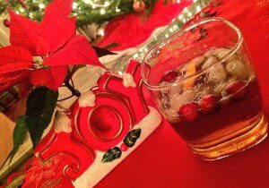 Festive holiday drink with cranberries and a poinsettia plant.
