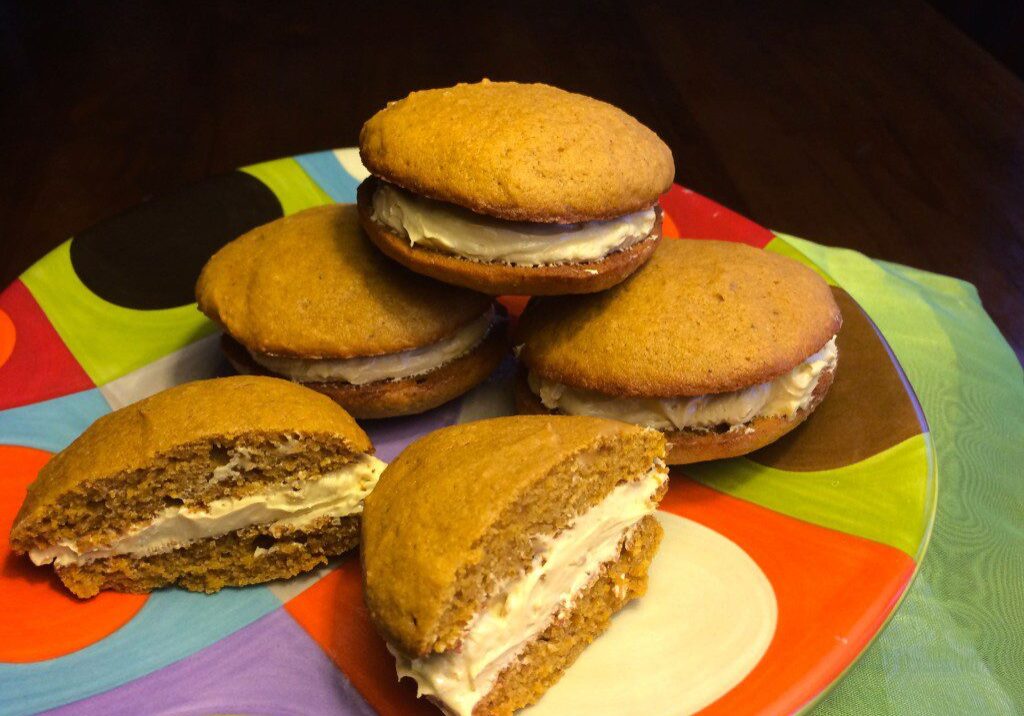 Stack of homemade whoopie pies with creamy filling on a colorful plate.