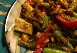 Plate of mixed vegetable stir-fry with tofu and colorful peppers.