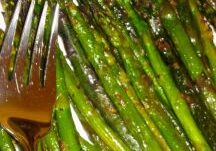 Grilled asparagus spears with seasoning and a fork.