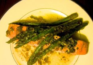 Grilled asparagus with seasoning on a white plate.