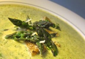 Creamy asparagus soup garnished with fresh asparagus tips.
