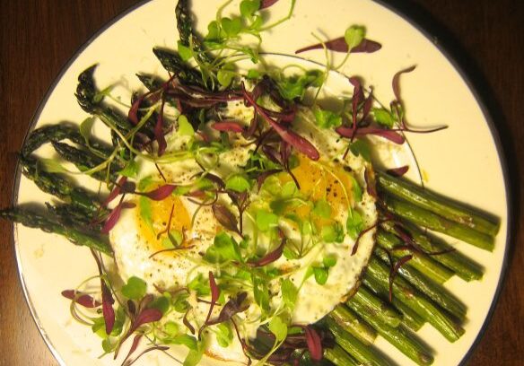 A fresh salad with greens and asparagus on a plate.