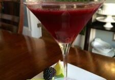 A vibrant red cocktail garnished with lime and berries.