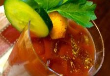 A glass of Bloody Mary garnished with cucumber and parsley.