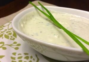 Bowl of creamy herb dip garnished with fresh chives.