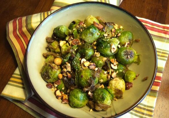 A bowl of roasted Brussels sprouts with chickpeas and nuts.