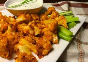 Buffalo cauliflower bites with ranch dip and celery sticks.