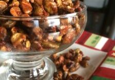 A glass bowl filled with caramel-coated popcorn on a festive tablecloth.