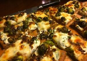 Close-up of a cheesy pizza with spinach and mushrooms.