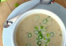 Creamy soup garnished with chopped green onions in a white bowl.