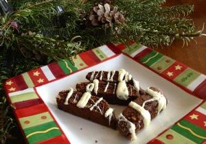 Holiday-themed chocolate dessert with white drizzle and sprinkles on a festive plate.