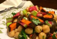 Colorful chickpea salad with fresh vegetables on a patterned plate.