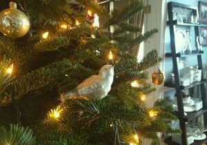 A white bird ornament on a Christmas tree with glowing lights.