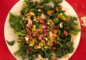 Fresh green salad with nuts and avocado on a white plate.