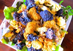 Colorful purple and orange cauliflower florets on a plate.