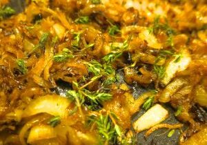 Close-up of caramelized onions garnished with fresh herbs.