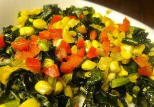 Sautéed kale with corn and diced tomatoes on a white plate.