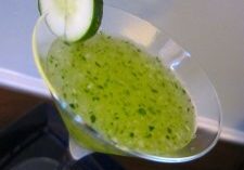 Green kiwi cocktail with a cucumber slice garnish.