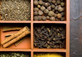 Assorted spices arranged in wooden compartments.