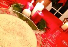 Festive holiday table with a bowl of dip and lit candles on a red tablecloth.
