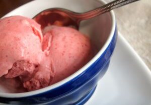 A bowl of pink strawberry ice cream with a spoon.