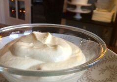 A glass bowl filled with creamy white mousse on a patterned plate.
